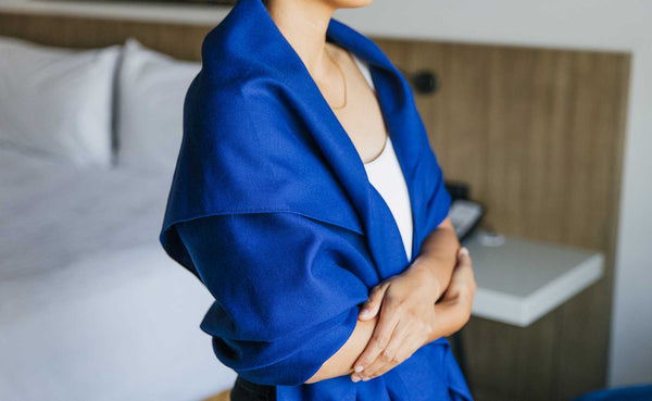 A Large Shepherd's Wool Utility Cloth in Neela Blue being worn by a person as a shawl; the person has their arms folded.